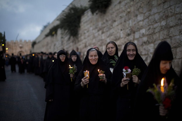 Nonnen pilgern mit Lichtern an einer Mauer vorbei