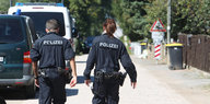 Zwei PolizistInnen gehen eine Straße entlang