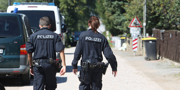 Zwei PolizistInnen gehen eine Straße entlang