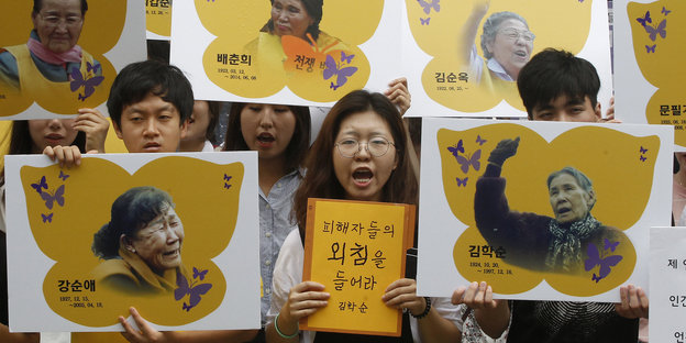 Menschen tragen gelbe Plakate mit den Fotos von Frauen