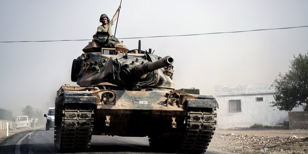 Ein Soldat schaut aus der Luke eines fahrenden Panzers