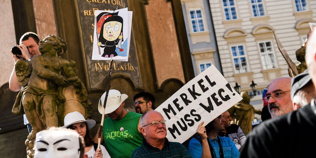Demonstranten halten ein "Merkel muss weg"-Plakat
