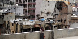 Eine Frau ist von hinten zu sehen als sie auf zerstörte Häuser der Stadt Cizre blickt
