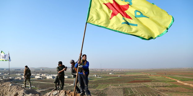 Männer mit einer Fahne der kurdischen YPG