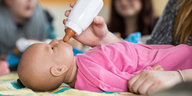 Eine Babypuppe wird mit einer Milchflasche gefüttert