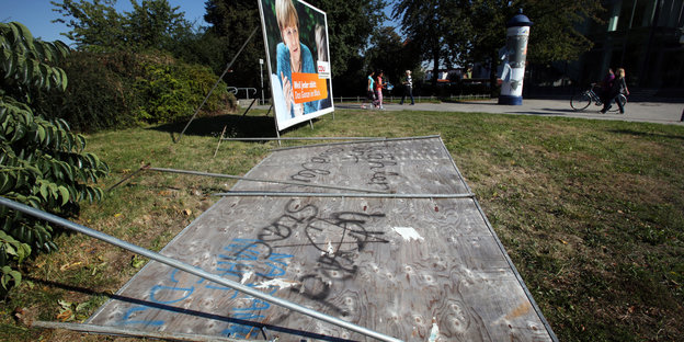 Ein großes umgeworfenes Wahlplakat neben einem anderen aufgestellten