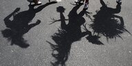 Drei Frauen werfen Schatten auf den Asphalt