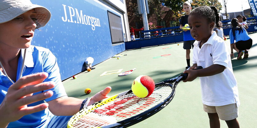 Tennislehrerin und Nachwuchs mit Schläger und Ball