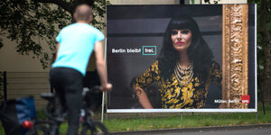 Ein Radfahrer fährt an einem Wahlplakat der Berliner SPD vorbei. Darauf ist zu sehen: Die Drag Queen Nina Queer und die Aufschrift „Berlin bleibt frei“