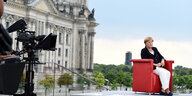 Angela Merkel sitzt auf einem Roten Sessel