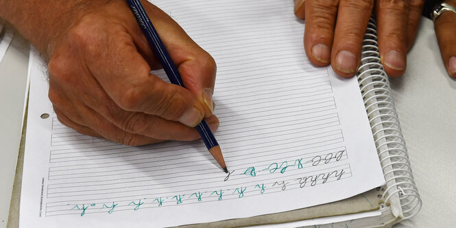 Eine Hand hält einen Stift und schreibt damit mehrfach den Buchstaben „h