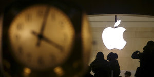 Links im Bild unscharf eine Uhr, rechts im Bild scharf gestellt das Apfel-Logo von Apple