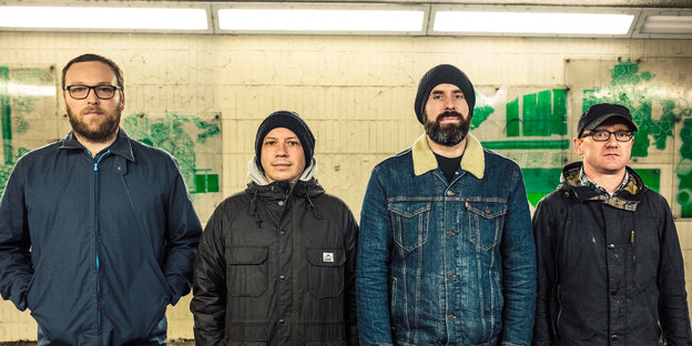 Die schottische Band Mogwai, vier Männer, steht in dicken Jacken in einem U-Bahnhof