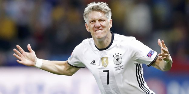 Ein blonder Mann in weißem Deutschlandtrikot beißt sichtlich euphorisch seine Zähne auf die Unterlippe Ein blonder Mann in weißem Deutschlandtrikot beißt sichtlich euphorisch seine Zähne auf die Unterlippe