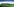 Eine Landschaft in Irland: grüne Wiese, eine See und im Hintergründ dunkle Berge