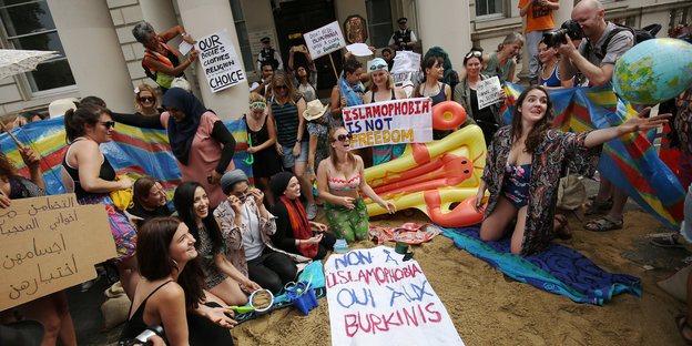 Eine Gruppe Frauen in Badeklamotten und mit Demo-Transparenten, die Stimmung ist gut