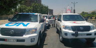 Ein Auto mit Aufschrift „UN“, daneben eines des Syrischen Roten Kreuzes