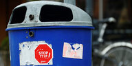 Auf einem blauen Mülleimer klebt ein roter Aufkleber mit der Aufschrift „Stop TTIP“