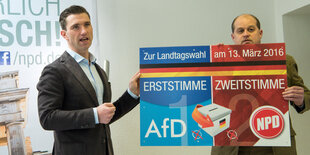 Zwei Männer halten ein AfD- und ein NPD-Plakat