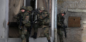 Soldaten mit Gewehren vor einem Haus