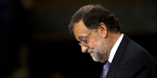 Mariano Rajoy mit gesenktem Kopf vor schwarzem Hintergrund