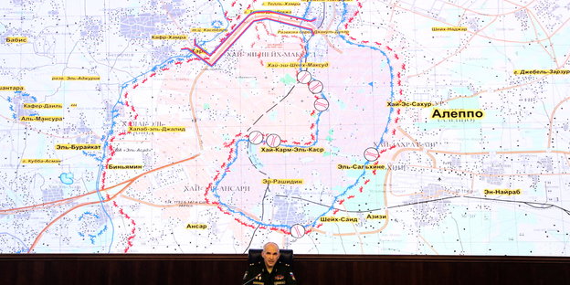 Der russische Generalleutnant Sergei Rudskoi sitzt vor einer sehr großen Karte von Aleppo