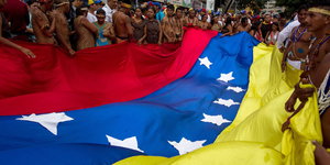 Menschen halten eine gigantische Venezuela-Flagge