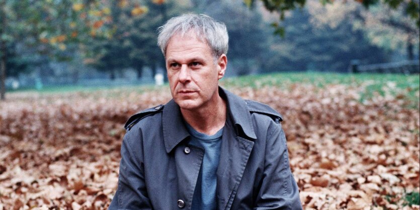 Dennis Cooper sitzt im Herbstlaub