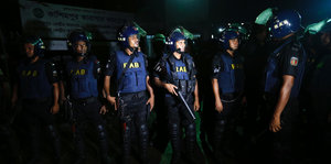 Bewaffnete Polizisten stehen im Dunkeln in einer Reihe