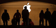 Silhouette mehrer Menschen vor dem Apple-Logo