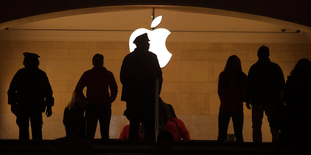 Silhouette mehrer Menschen vor dem Apple-Logo