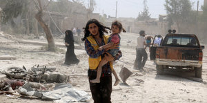 Mann mit Kind auf dem Arm im zerstörten Aleppo