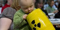 Ein kleines Kind schaut in einen Spielzeugcontainer für radioaktiven Abfall