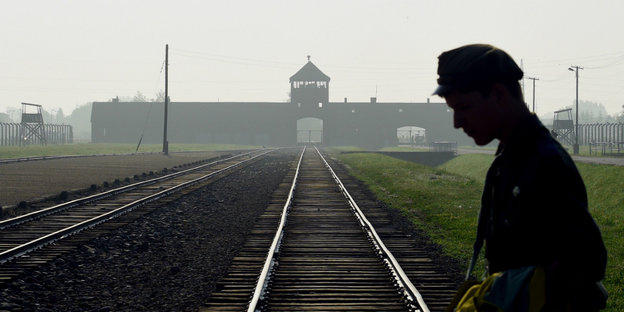 Silhouette eines Mannes mit Mütze vor der Rampe von Auschwitz