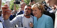 Ein Migrant macht ein Selfie mit Angela Merkel