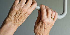 Hände einer älteren Person fassen nach einem Griff im Krankenhaus