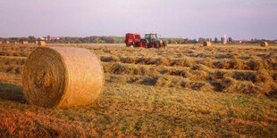 Ein Traktor und ein Strohballen in der Abendsonne