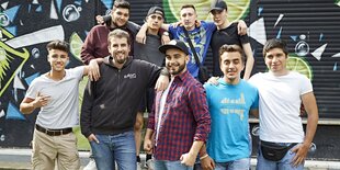 Jungs machen zusammen ein Gruppenbild, hinter ihnen ist ein Graffiti an die Wand gemalt