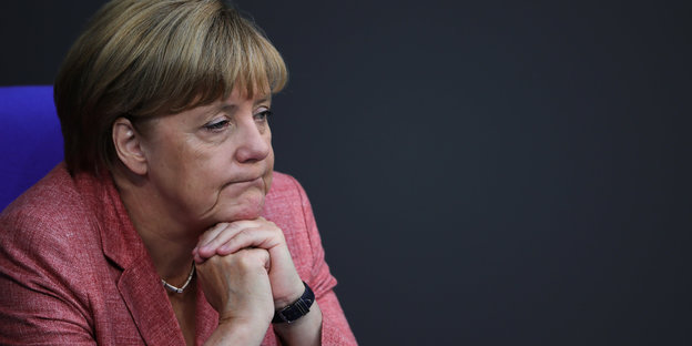 Angela Merkel sitzt mit ihrem Kinn auf ihren Händen