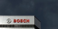 Firmen-Logo am Gebäude der Konzernzentrale, darüber dunkler Himmel