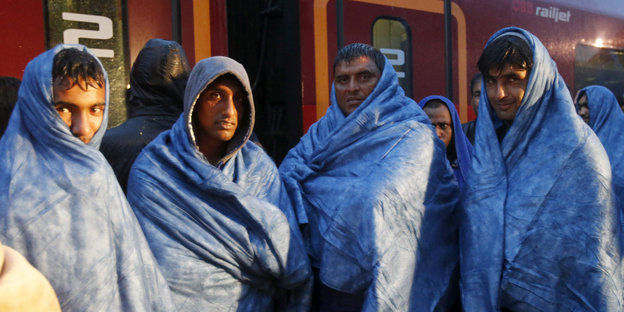 Vier Flüchtlinge in Decken gehüllt