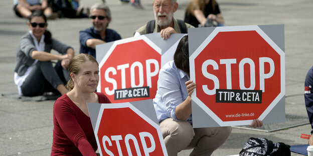 Protestierende sitzen mit Stop-Ceta/TTIP-Schildern auf dem Boden