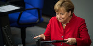 Angela Merkel steht an einem Rednerinnenpult und bläst die Backen auf