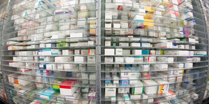 Zahlreiche Arzneimittelpackungen in einem Regal, das Bild ist mit einer Fischaugenlinse aufgenommen, die Ränder sind unscharf