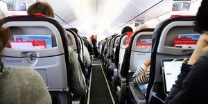 Fluggäste sitzen mit dem Rücken zum Betrachter in einem Flugzeug