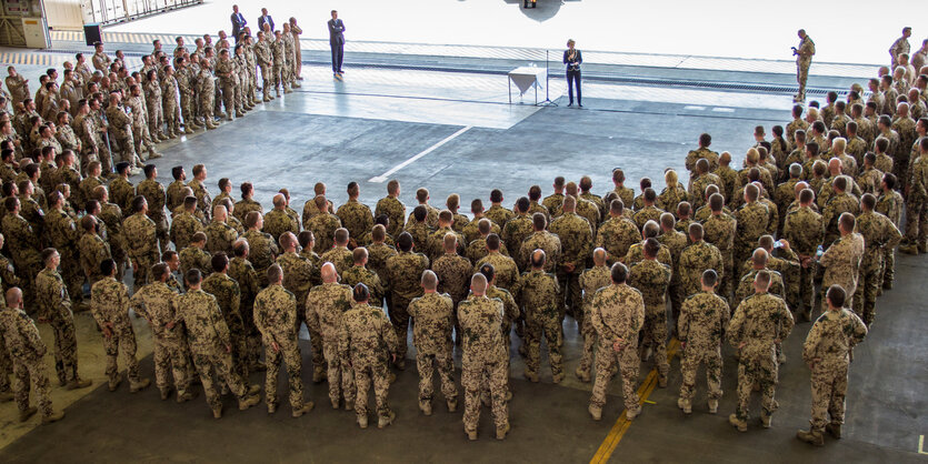 Bundeswehr-Soldaten stehen auf einem Platz zusammen, eine Frau spricht zu ihnen