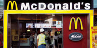 Ein Mann mit einem Bauarbeiter-Helm geht in eine Filiale von McDonalds
