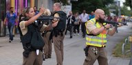 Polizisten und Polizistinnen in Schutzkleidung und mit Waffen sehen aufgeregt in verschiedene Richtungen