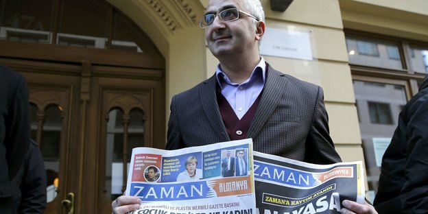 Ein Mann hält zwei Zeitungen in der Hand