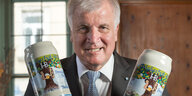 Horst Seehofer hält grimmig lächelnd zwei Bierkrüge in den Händen